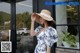 a woman wearing a straw hat standing in front of a window