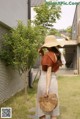 A woman wearing a straw hat and holding a basket bag.