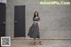 A woman standing in front of a wall wearing a black and white striped dress.