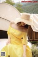 A woman in a yellow dress and a straw hat.