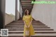 a woman in a yellow dress standing on some steps