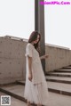 a woman in a white dress standing on some steps