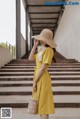 a woman wearing a yellow dress and a straw hat