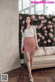 a woman standing in front of a couch wearing a pink skirt