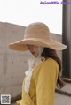 a woman wearing a yellow shirt and a straw hat