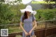 A woman in a blue dress and a white hat holding a basket.