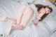 A woman in a white lingerie laying on a bed.