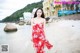 A woman in a red dress walking on a beach.