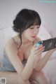 A woman sitting on a bed playing a video game.