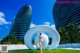 A woman in a blue bikini standing in front of a large white sculpture.