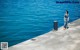 A woman standing on a pier by the water.