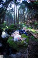 A woman laying on a rock in the woods.