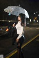 A woman standing in the rain holding an umbrella.