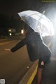 A woman holding an umbrella in the rain at night.