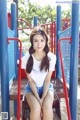 A woman sitting on a bench in a playground.