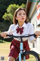 A woman in a school uniform riding a bike.